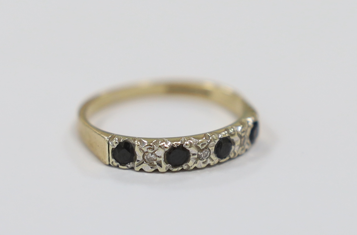 A modern 9ct gold, four stone sapphire and three stone diamond chip set half hoop ring, size N, gross weight 2 grams.